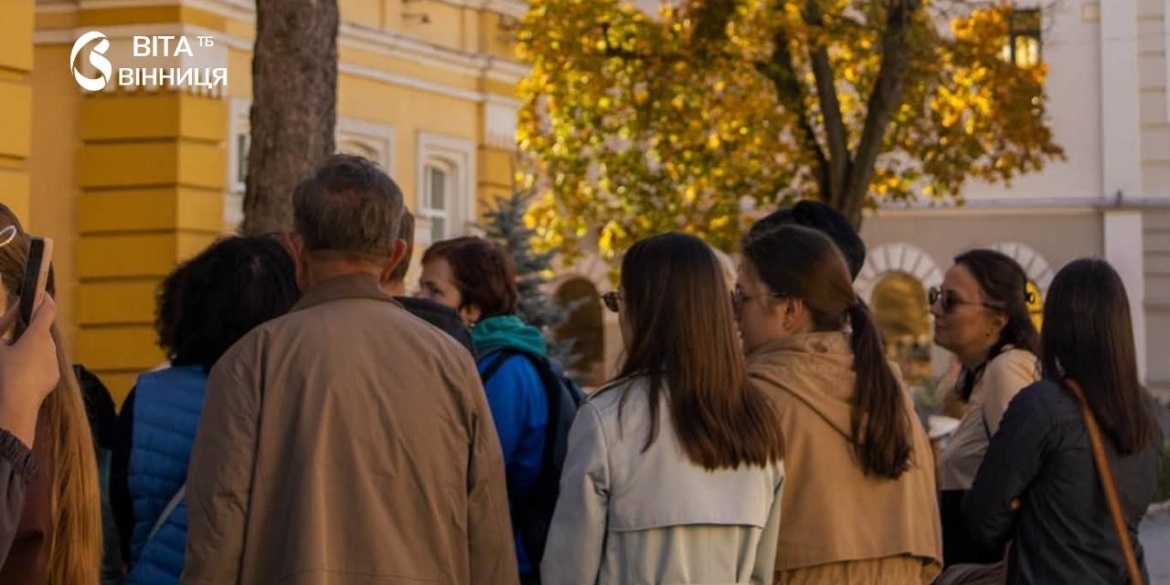 Гід із групою туристів на екскурсії вулицями Вінниці серед історичних будинків осіннього дня