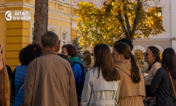Гід із групою туристів на екскурсії вулицями Вінниці серед історичних будинків осіннього дня Гід із групою туристів на екскурсії вулицями Вінниці серед історичних будинків осіннього дня
